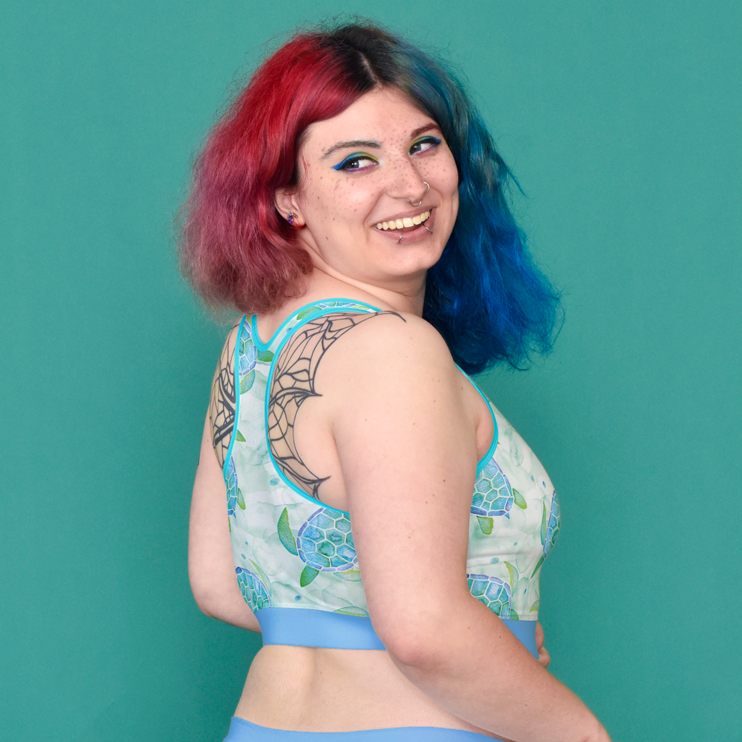 Autumn looking backwards over their shoulder wearing a Turtles print racerback bralette.