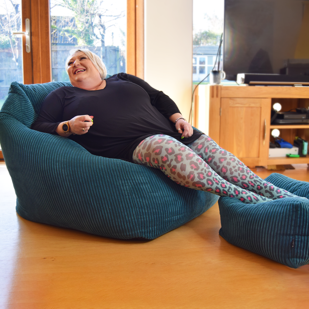 Julie is sitting wearing hot leopard print tights on a teal beanbag