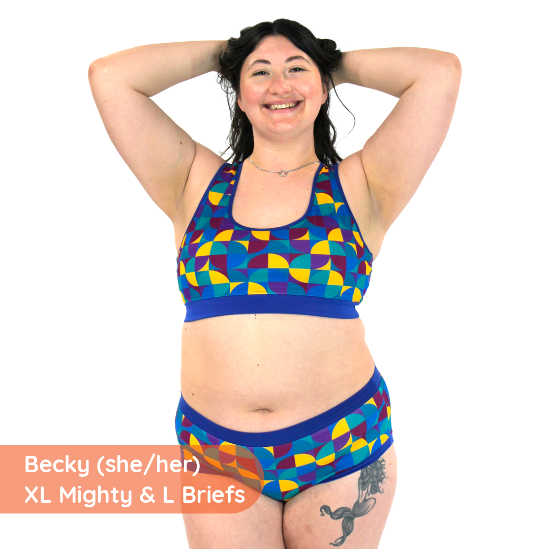 Becky has her arms up wearing a racerback bralette and cotton briefs