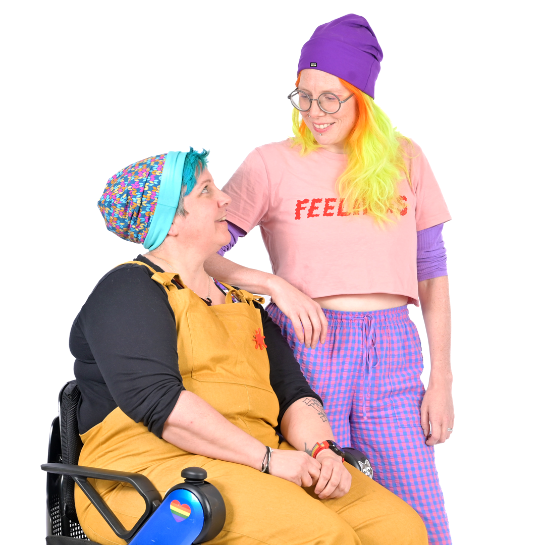 Kirsty and Jen wearing colourful beanies looking at each other