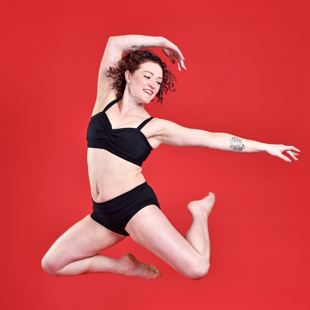 Jenni is mid leap wearing a black cotton underwear set