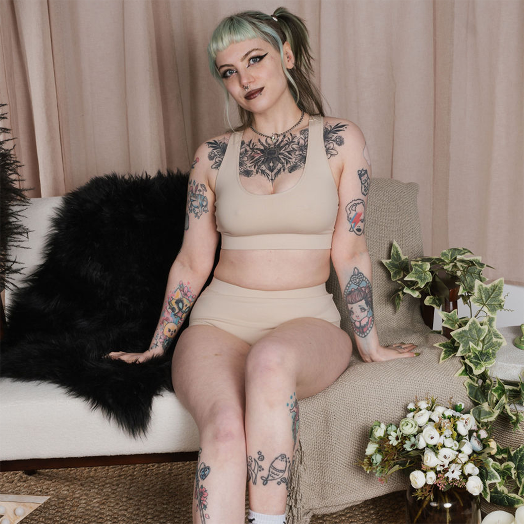 Faeryn posing on the sofa in a nude skin tone underwear set