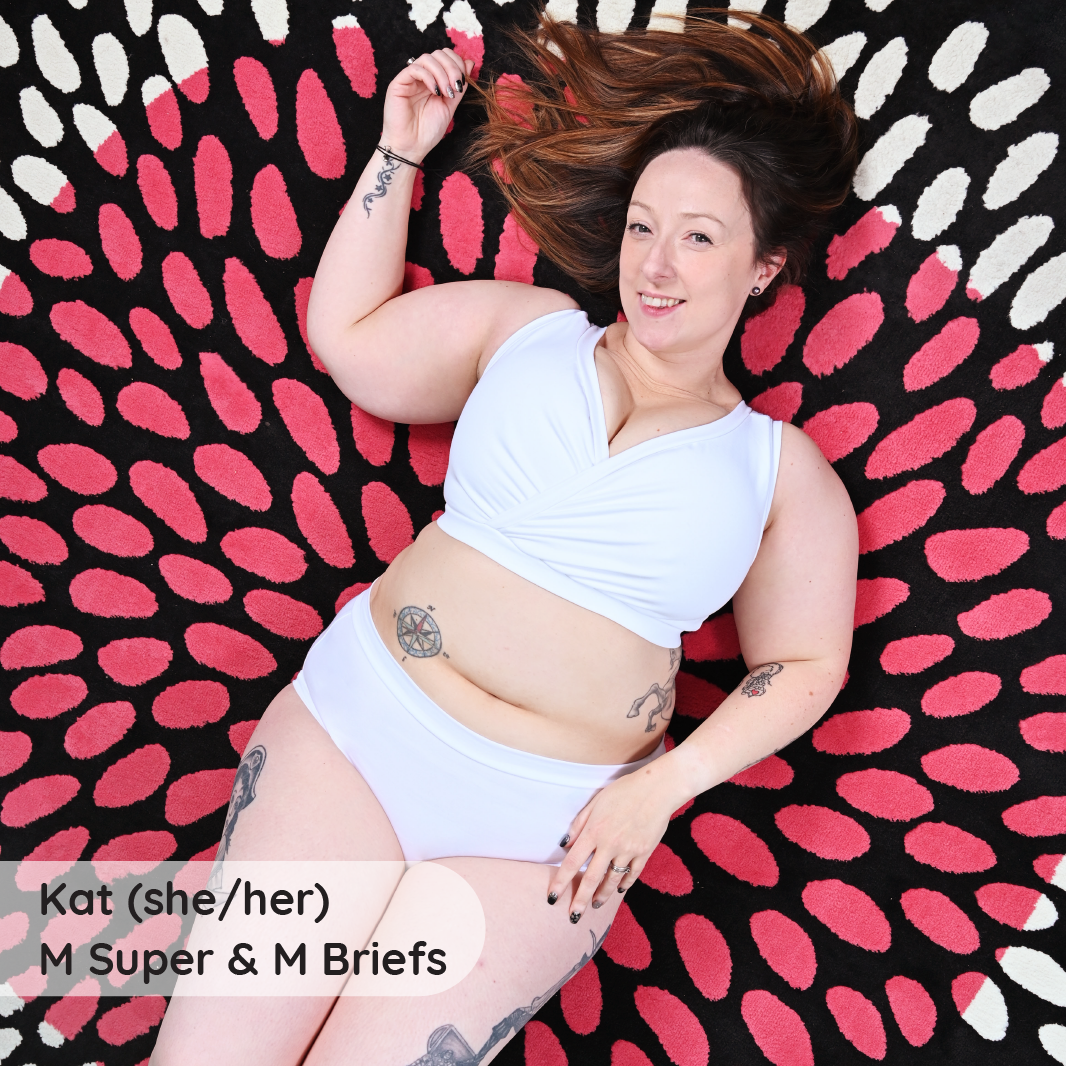 Kat is laid on a colourful rug wearing a white underwear set