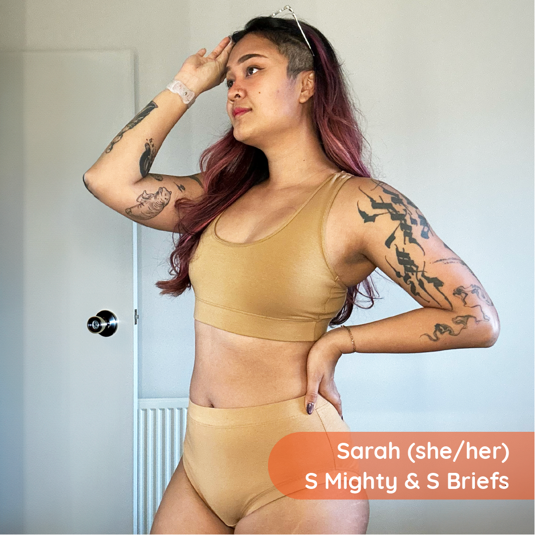 Woman wearing beige sports bra and high-waisted underwear with 'Sarah (she/her) S Mighty & S Briefs' text.