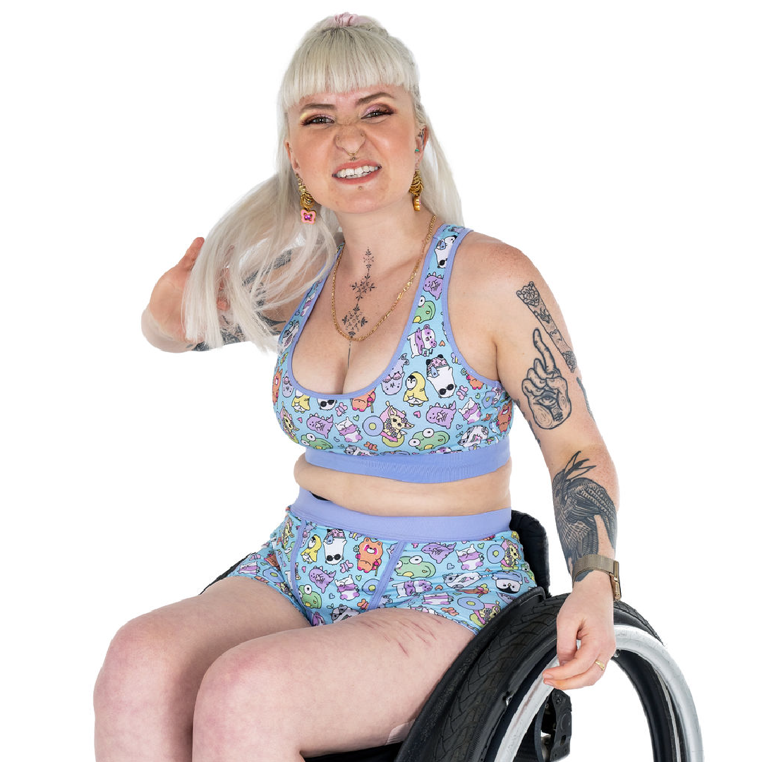 Jess is smiling sitting in her wheelchair wearing a sugar and sloth bralette and boxers