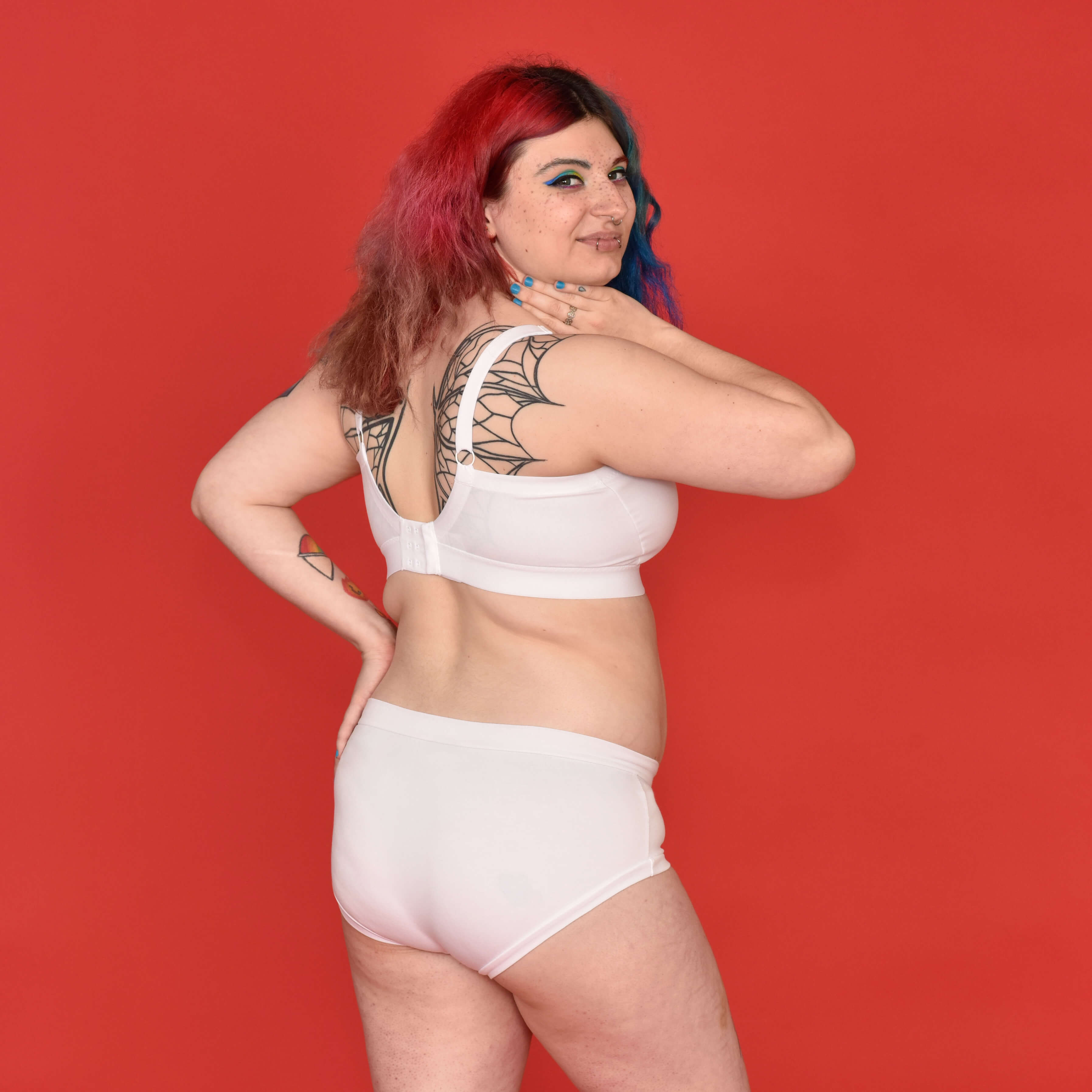 Autumn is wearing a white underwear set looking over their shoulder