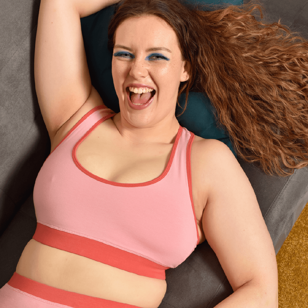 Alice is wearing a candyfloss pink racerback bralette laid on the sofa