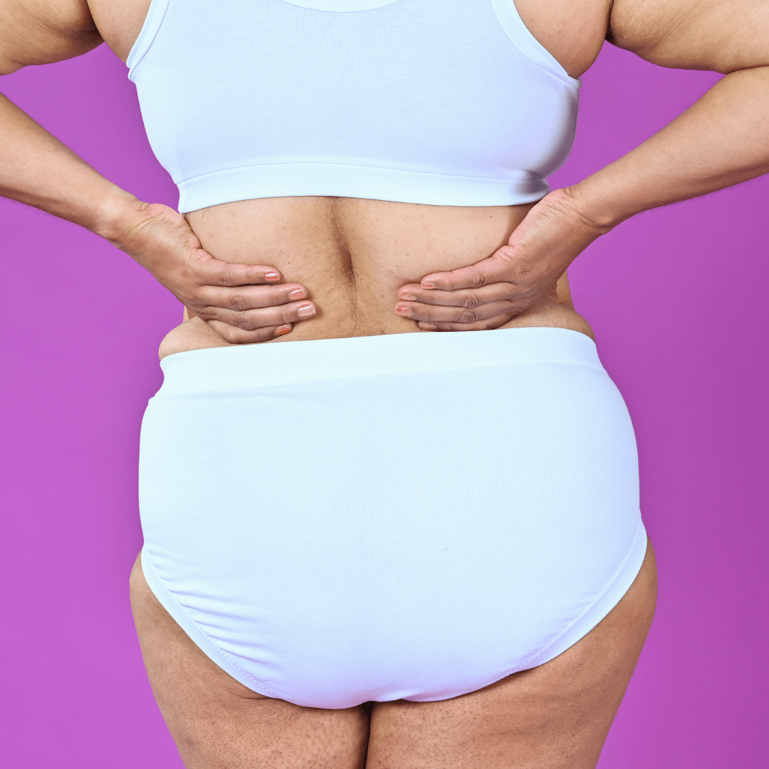 Back view of Anita wearing white high rise briefs and bra